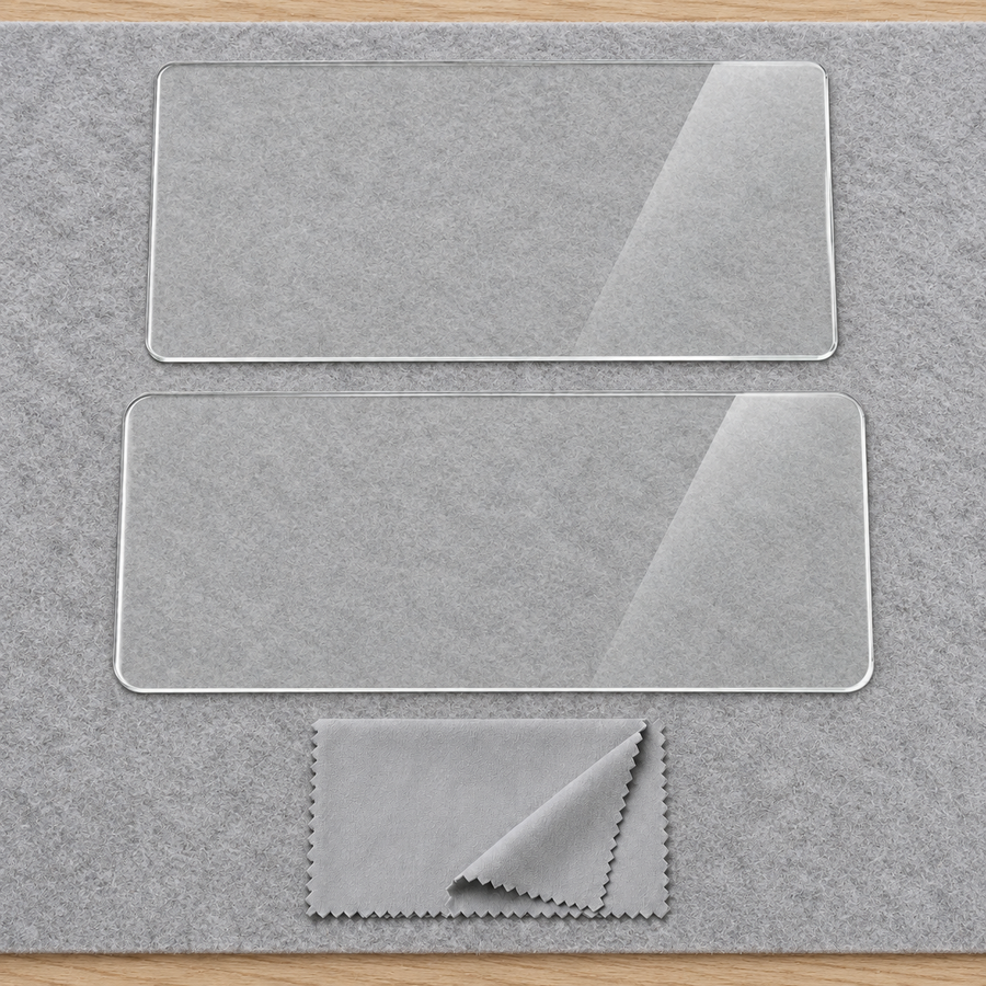Two uninstalled clear display protector sheets and a folded gray cloth on a plain felt inspection mat.