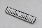 Silver openwork vent grille resting on a grey inspection surface
