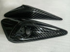 Pair of glossy exterior camera trim covers with circular lens openings on protective foam