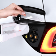 Supplier-derived installation reference showing a hand lifting the translucent TPU cover beside the white charging connector; charger and vehicle are not included.